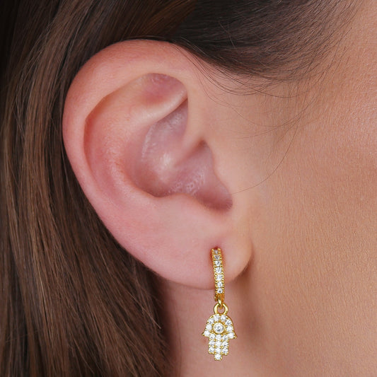 Brinco Lilith Allure Dourado Argolinha Mãos de Fátima Cravejado Zircônia. Lilith Allure Gold Huggie Hoops with Zirconia-Studded Hamsa Charms